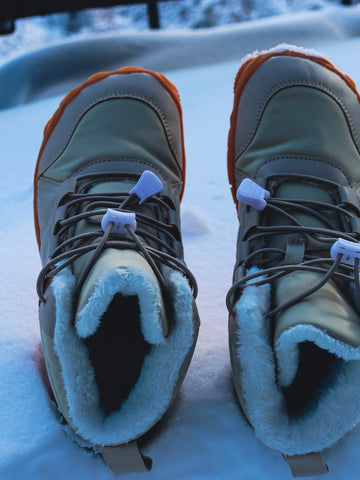 HYKLE barefoot boots standing in fresh snow